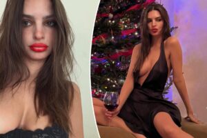 Emily Ratajkowski wears a plunging black satin dress in front of Christmas tree in Instagram post