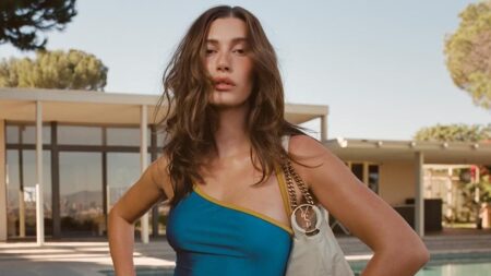 Hailey Bieber has a Wonder Woman moment in a swimsuit and gold bangles while boldly parting her legs