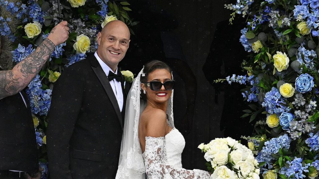 And the bride wore… Crocs, sunglasses, had a 50 ft train and clutched her phone as she arrived at church! Venezuela Fury’s very unique bridal look
