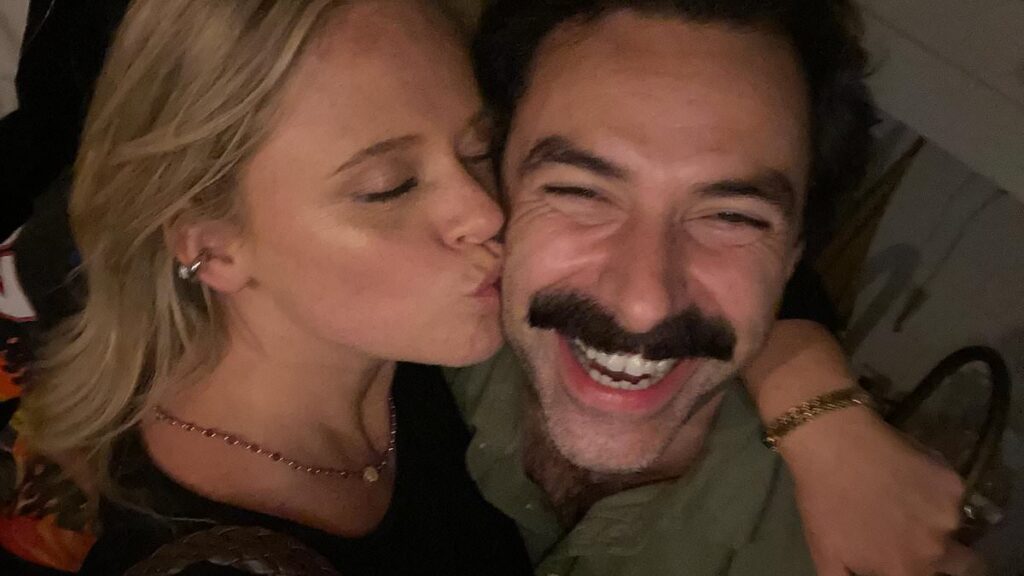Emily Atack plants a kiss on co-star Aidan Turner’s cheek as she shares a slew of behind-the-scenes snaps from filming Rivals series two