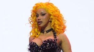 Cardi B shows off her hourglass curves in a fishnet bodysuit and latex harness with a neon yellow wig as she performs in New Orleans